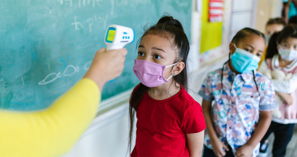 Young girl stands first in line in an elementary school classroom to get her temperature checked